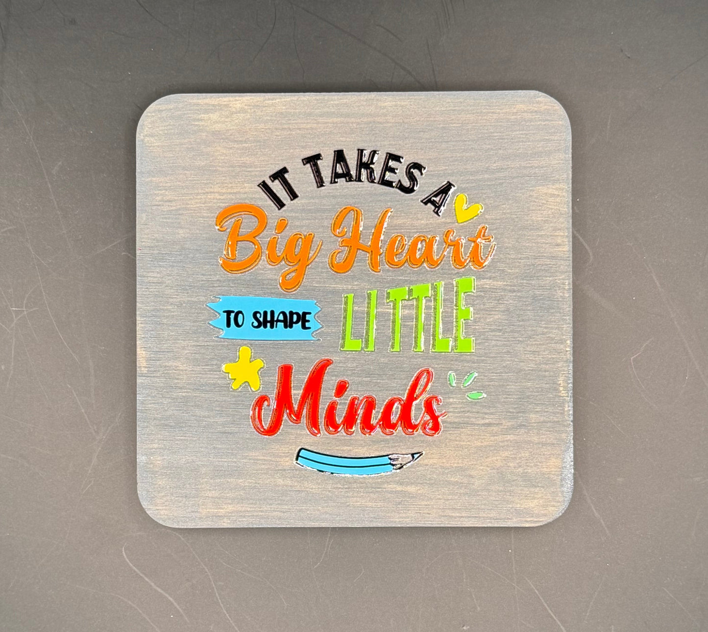 Decorative coaster with colorful text on a dark surface