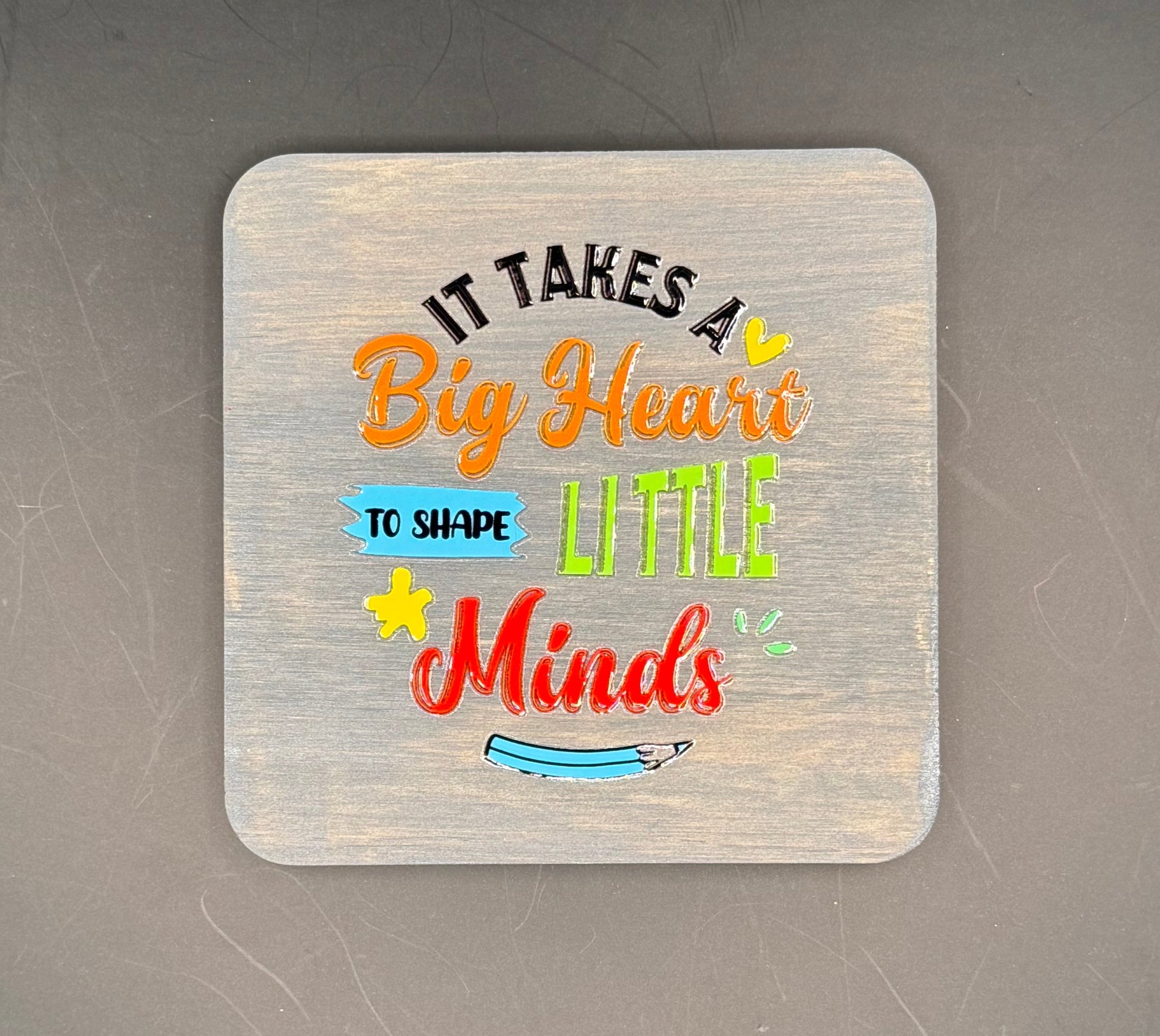Decorative coaster with colorful text on a dark surface